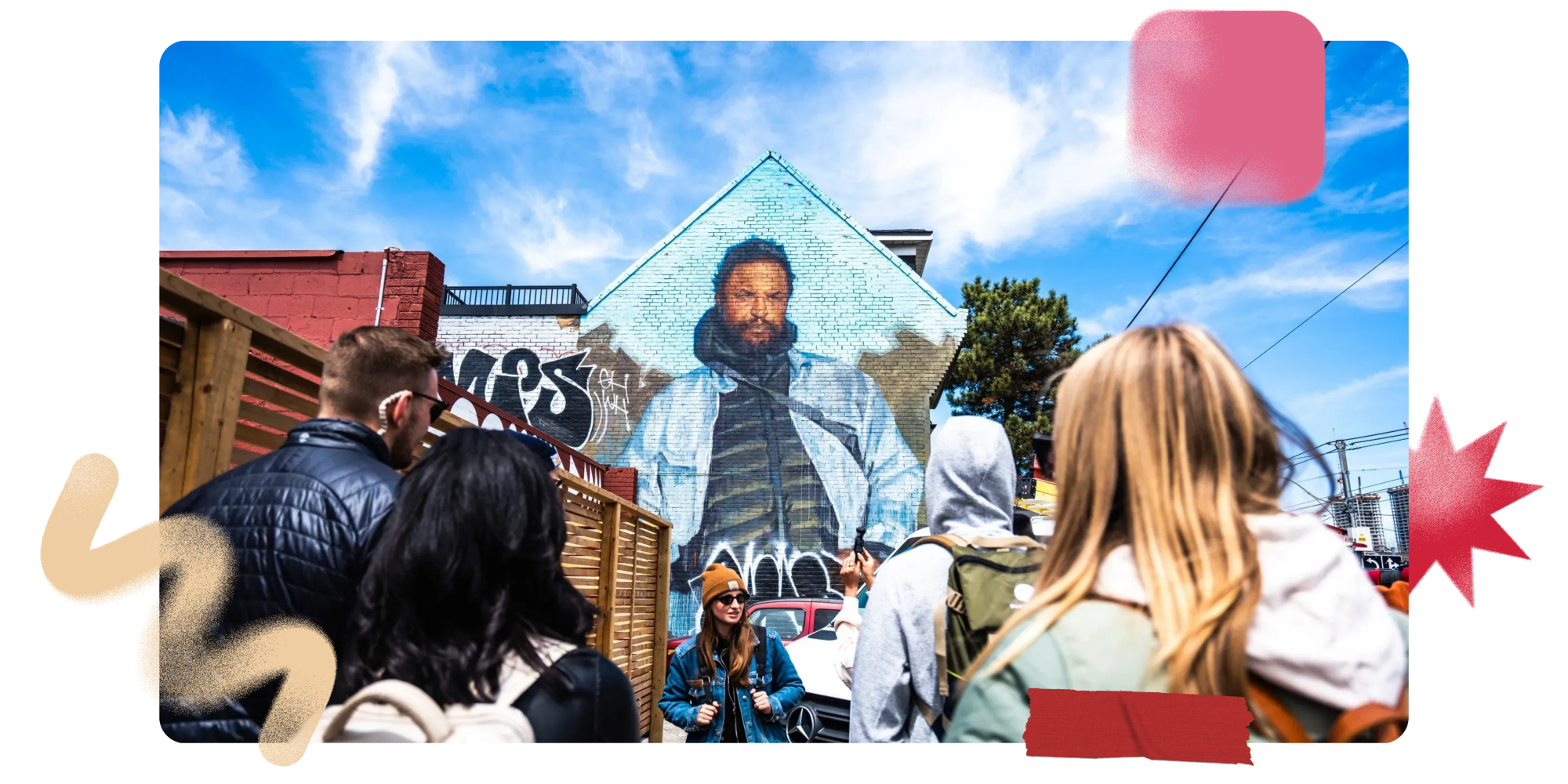 Group of people looking at a mural painted on a building wall.